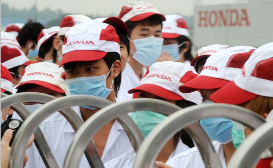 Striking workers wearing masks gather May 26 outside a plant  in China's Guangdong province that manufactures auto parts for Honda. Strikes by workers demanding higher wages have halted production at three Honda plants in southern China recently.