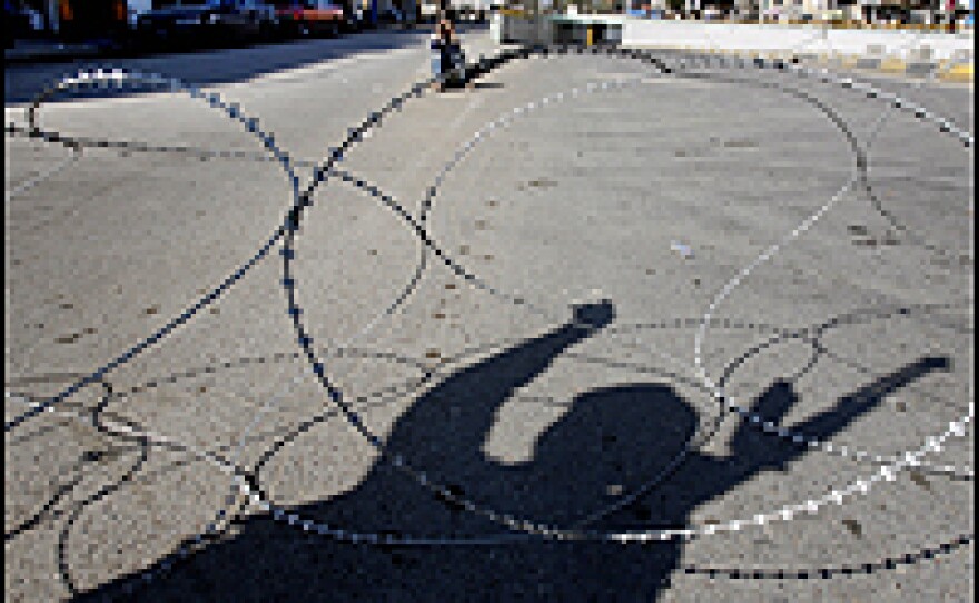 The shadow of an Iraqi soldier falls across barbed-wire as he mans a checkpoint in central Baghdad.