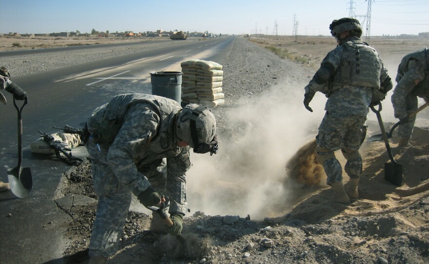 Soldiers fill a hole left by an explosion on a road outside Beiji, Iraq, in 2005. In his debut novel, Michael Pitre follows a group of Marines doing similar work on Iraq's highways.