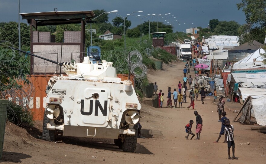 Some of the more than 30,000 Nuer civilians sheltering in a United Nations base in South Sudan's capital Juba for fear of targeted killings by government forces walk by an armored vehicle and a watchtower manned by Chinese peacekeepers.