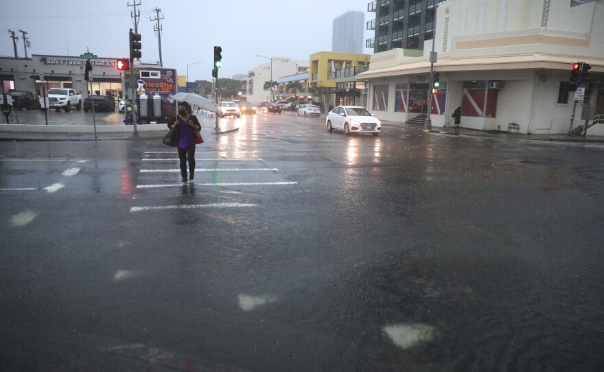A pedestrian tries to cross a flooded Queen Street, Monday, Dec. 6, 2021, in Honolulu.