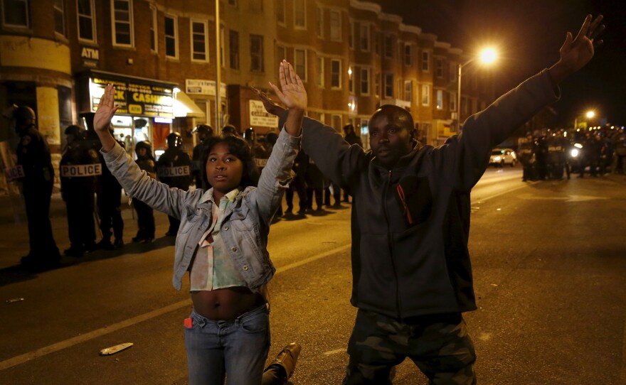 People kneel in front of riot police Wednesday along Pennsylvania Avenue in Baltimore, past the curfew. The two were among the few to defy the curfew as Baltimore remained relatively quiet two days after rioting and looting.