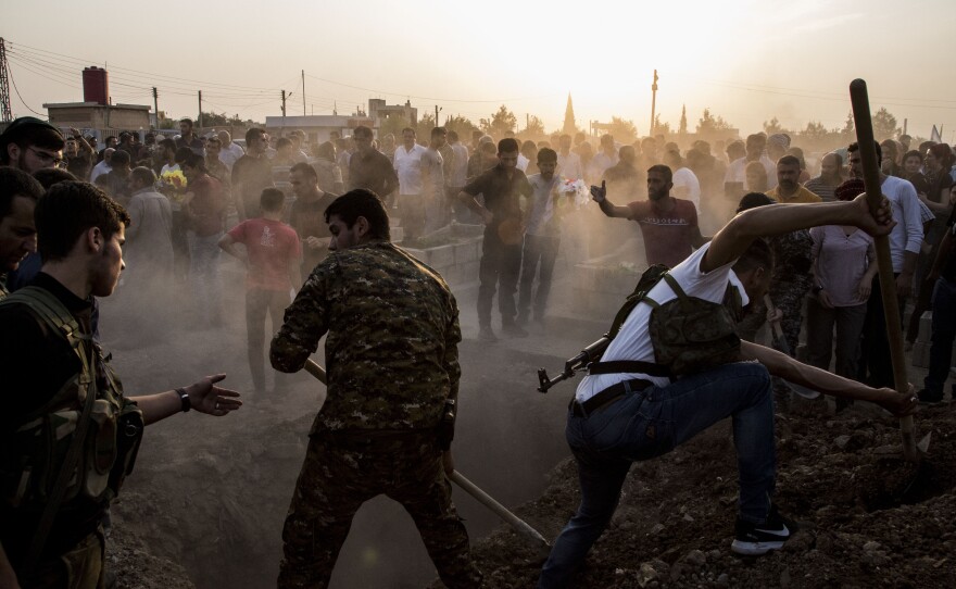 Syrians bury Syrian Democratic Forces fighters killed while battling Turkish forces in the town of Qamishli on Saturday. Turkey's military says it has captured a key Syrian border town as its offensive against Kurdish fighters presses on.