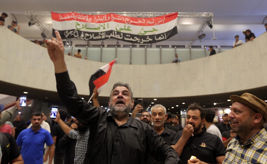 Iraqi protesters pose with national flags inside the Parliament building in Baghdad on Sunday.
