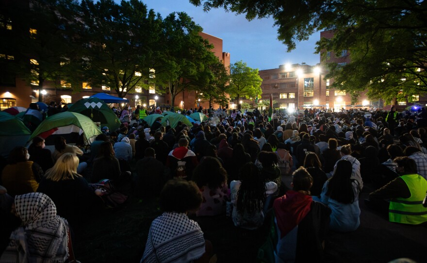 Thousands of people sit silently while fellow demonstrators pray during a rally at George Washington University on Thursday night.