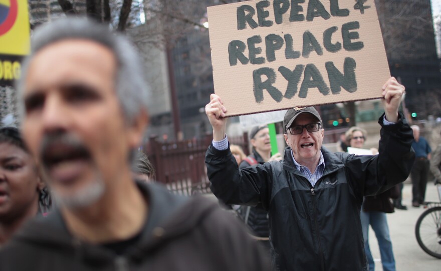 Demonstrators gather near Trump Tower after the defeat of the GOP health care plan. One man holds up a sign, urging the ouster of House Speaker Paul Ryan, who spearheaded the failed effort.