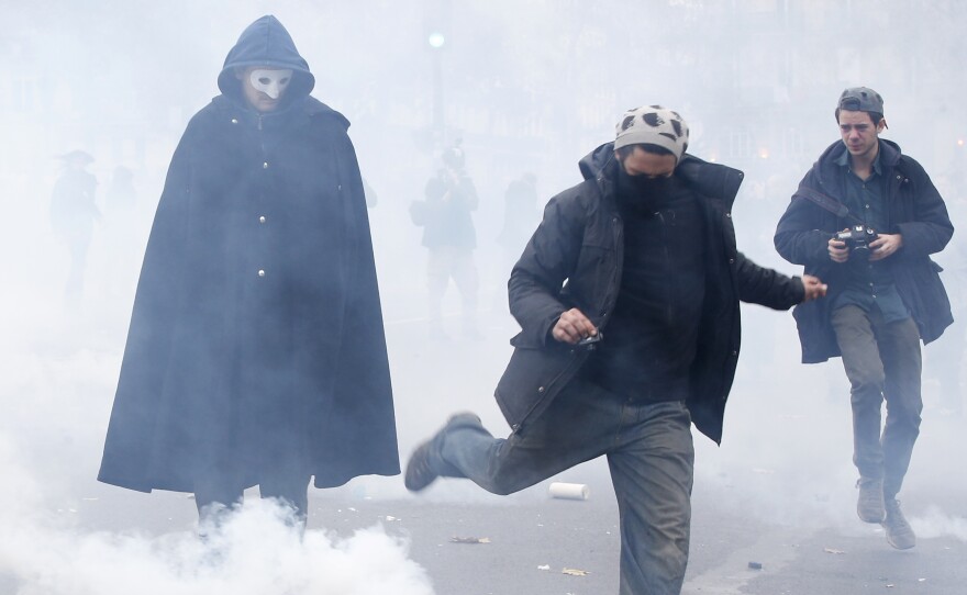 A demonstrator kicks a tear gas canister during clashes with riot police near the Place de la République after the cancellation of a planned climate march.