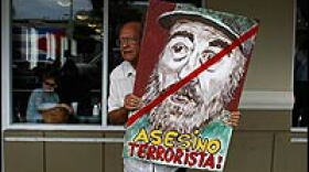 Alfredo Rey holds a painting of Cuban President Fidel Castro that reads, "Assassin terrorist," in the Little Havana neighborhood of Miami, Fla.
