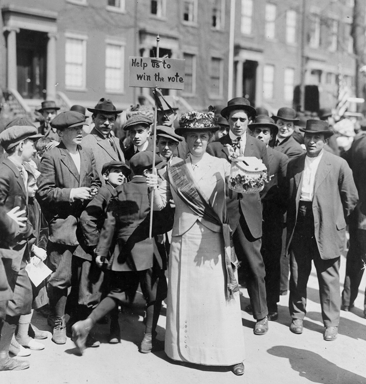 Suffragist, "Mrs. Suffern," holding sign; crowd of boys and men behind. N.Y., 1914.