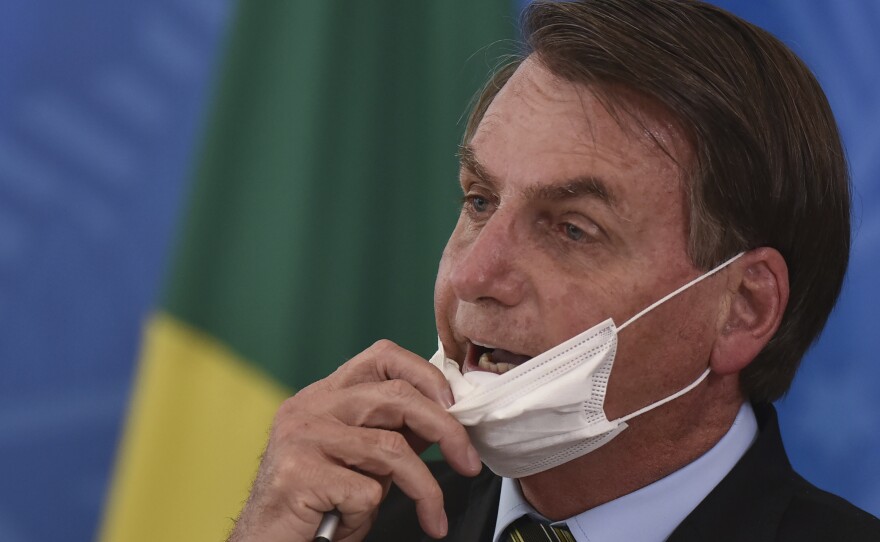 Brazil's President Jair Bolsonaro removes his mask to speak to journalists after a press conference on the coronavirus on Wednesday.