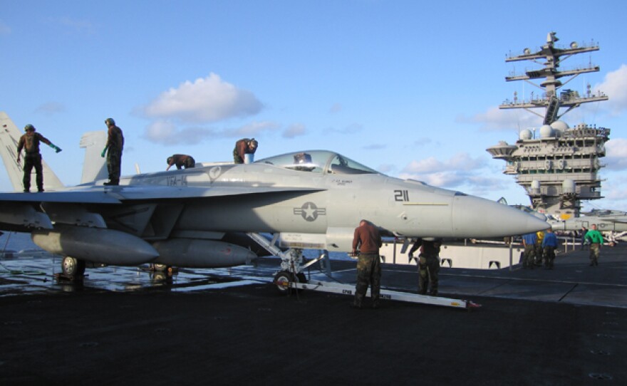 Airmen maintain an F/A-18E Hornet, flown by Strike Fighter Squadron 14 (VFA-14), aka "The Top Hatters," aboard the USS Nimitz.