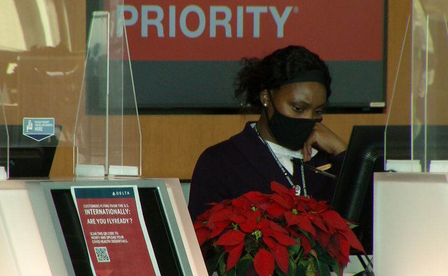 A Delta employee stands behind a ticket counter inside of the San Diego Airport's terminal two near downtown, Dec. 3, 2021.