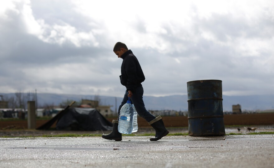 A Syrian refugee child carries water in the Fayda Camp, some 25 miles east of Beirut, Lebanon, on March 10.