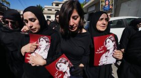 Mourners hold posters that show portraits of Lebanese journalist Amal Khalil, who was killed Wednesday in an Israeli airstrike, during her funeral procession in the village of Baysariyeh, in southern Lebanon, on Thursday.