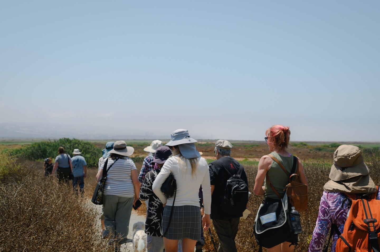 Attendees follow as volunteer docent Ron Peterson leads his tour, “An Eye-Opening Experience Without Sight,” through the Tijuana River Estuary in Imperial Beach, California on August 3, 2024.