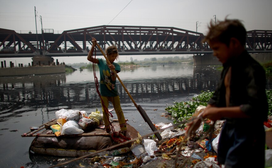 In the shadow of the British colonial Old Iron Bridge, children ply the Yamuna River in makeshift rafts and scour its banks in search of anything valuable to help their families eke out an existence.