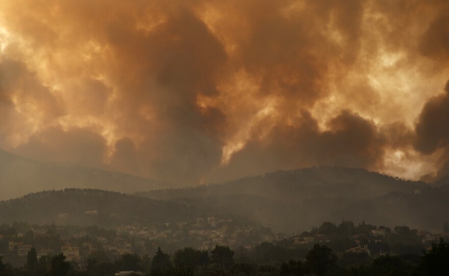 Smoke spreads over Parnitha mountain during a wildfire in Ippokratios Politia village, about 21 miles north of Athens, Greece on Friday. Thousands of people fled wildfires burning out of control in Greece and Turkey on Friday, including a major blaze just north of the Greek capital of Athens.