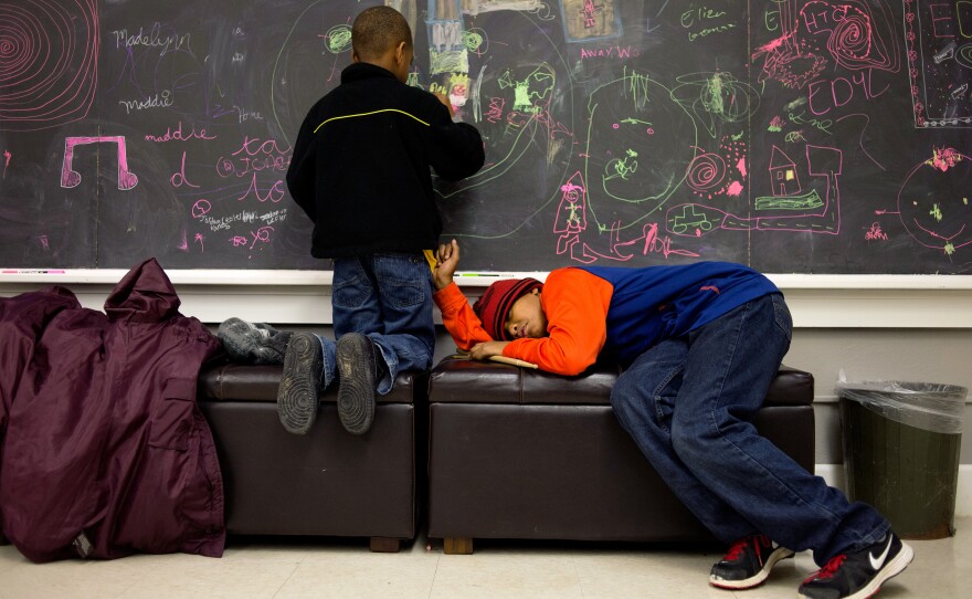 Nikia Cliff II, 6, colors on the chalkboard inside the Major Chords for Minors office before his piano lesson while his older brother Khalil Cliff, 10, takes a nap before his drum lesson.