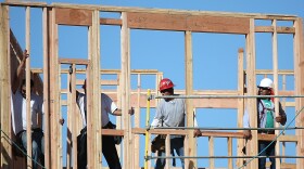 Construction workers move a framed wall into place at a new housing development in San Mateo, Calif.