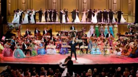 A photo of the Dresden’s Semper Opera House stage and performers with the bride and groom dancing in front. Andre Rieu’s latest program is both a concert and a real wedding party in one of the world’s most beautiful opera houses.  