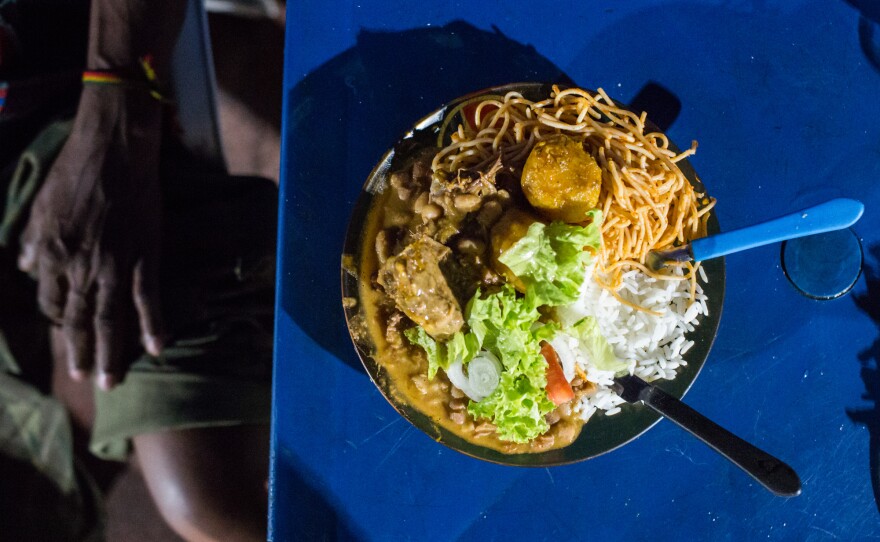 Antonio Carlos "Carlinhos" da Silva Costa, 49, eats spaghetti, beans and chicken at a food stall in Bahia, Brazil.