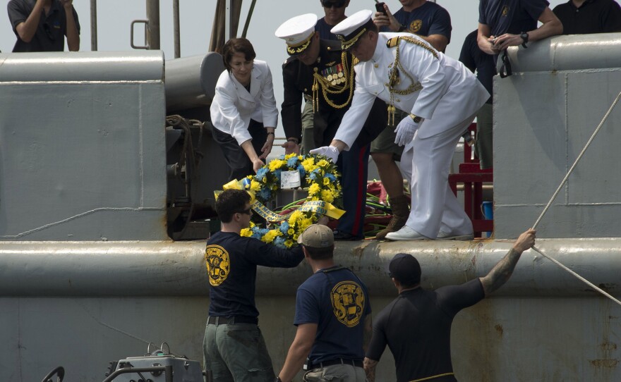 Deputy Chief of Mission (Jakarta, Indonesia) Kristen Bauer (top left), Capt. Richard Stacpoole (top right), and Marine Lt. Col. Miguel Avila pass a wreath to sailors, assigned to Mobile Diving Salvage Unit One, during a wreath-laying ceremony for the sunken Navy vessel USS Houston.