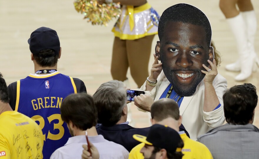 A fan holds up a cutout of Draymond Green's face Monday night. The Golden State Warriors player was suspended for Game 5 of the NBA Finals because of a flagrant foul he committed in the previous game.