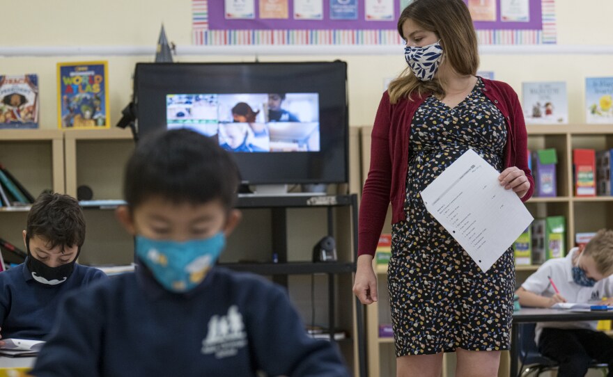 A teacher wearing a protective mask walks around the classroom during a lesson at an elementary school in San Francisco in October 2020.