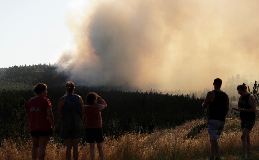 People watch Old Trails Fire from W. Northwest Blvd., Saturday, Aug. 1, 2026, in Spokane, Wash.