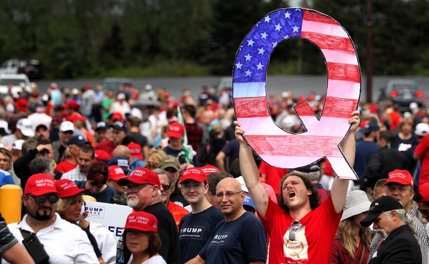 David Reinert holds up a large "Q" sign that represents QAnon while waiting in line to see then-President Donald Trump at his rally in Wilkes Barre, Pa., on Aug. 2, 2018.