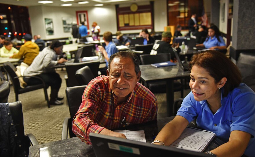 Elisa Carrero assists Julian Gauiria, of Paterson, N.J., with enrollment in the health insurance exchange in November. Signups continue to be brisk, health officials say.