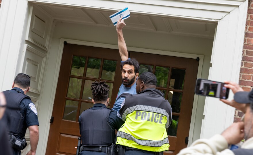 Pro-Palestinian demonstrators occupy the University Yard of The George Washington University in downtown Washington, D.C. on Thursday. A person with an Israeli flag argued with the group of Pro-Palestinian demonstrators and had to be escorted away and into a university building by GWU police.