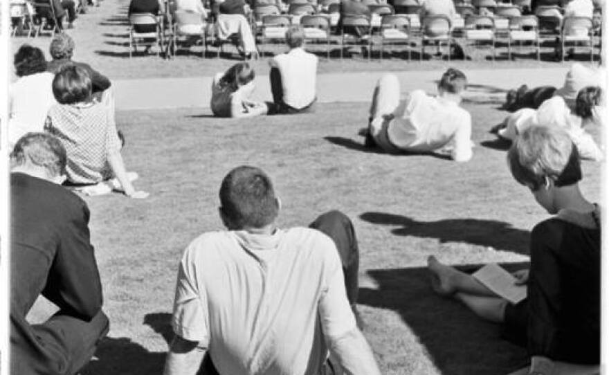Spectators fill the seats and some sit in the grass at the 1967 convocation for Muir College.