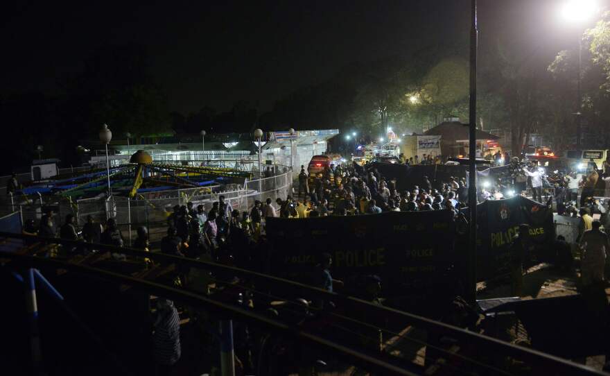 Officials and rescuers gather at the blast site, next to an amusement ride.