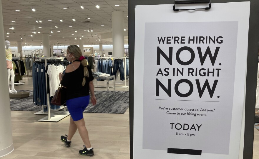 A customer walks behind a sign at a Nordstrom in Coral Gables, Fla., store seeking employees in May.