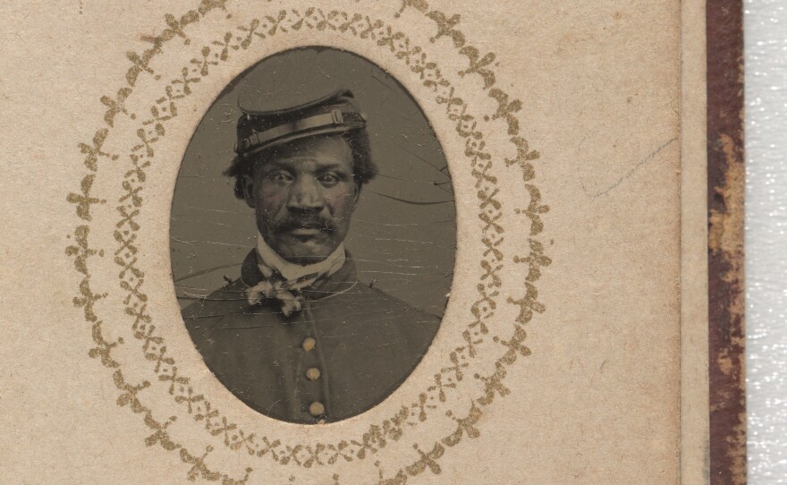 A black-and-white photograph of William H. Morris. He is wearing a buttoned-up jacket with epaulets on the shoulders and a kepi. His kepi has a leather chin strap resting on the brim and is on the right side of his head. His name is inscribed below the photograph on the same page.