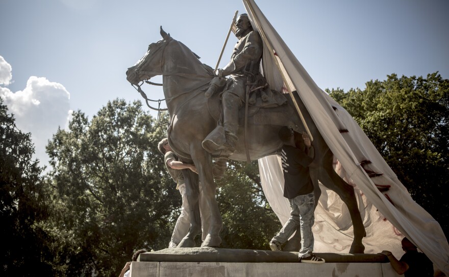 Protesters attempt to cover a statue of Ku Klux Klan leader Nathan Bedford Forrest at Health Sciences Park in Memphis, Tenn., in August 2017. The statue was removed in December.