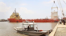A policeman keeps watch as a four-story pollution control chamber which will be lowered 5,000 feet below the surface of the water to capture oil gushing from the collapsed oil well off the coast of Louisiana sits on the back of a ship as it leaves the dock May 5, 2010 in Port Fourchon, Louisiana. 