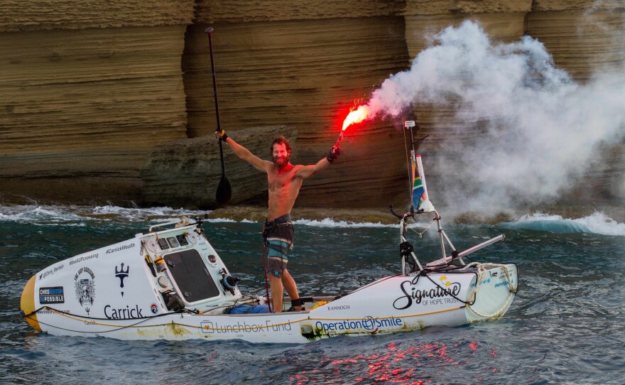 Chris Bertish enters the English Harbour at Antigua on Thursday, a flare trailing behind him in celebration. He paddled more than 4,050 nautical miles to reach this point.