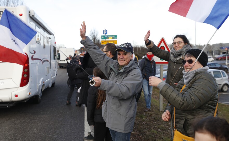 People wave to a convoy departing for Paris on Friday in Strasbourg. Authorities in France and Belgium have banned road blockades threatened by groups inspired by protesters in Canada.