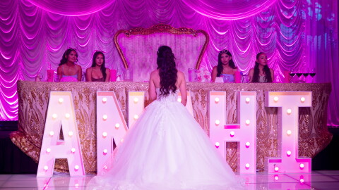 Anahi Sareñana talks to her friends while on stage during her quinceañera at the Factory of Dreams hall in Chula Vista, May 31, 2026.