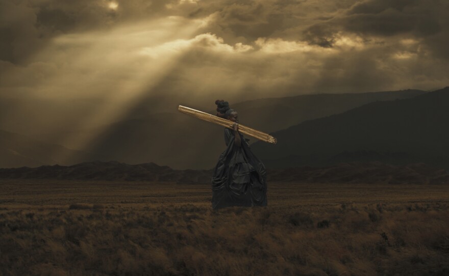 In <em>Rwendo</em>, an African woman in an old-fashioned satin gown traverses a somber landscape.