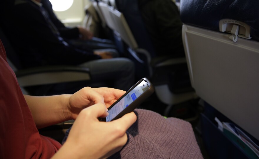 The new head of the Federal Communications Commission proposes allowing airline passengers to make phone calls during flights. Here, a passenger looks at her cellphone before a flight last month.