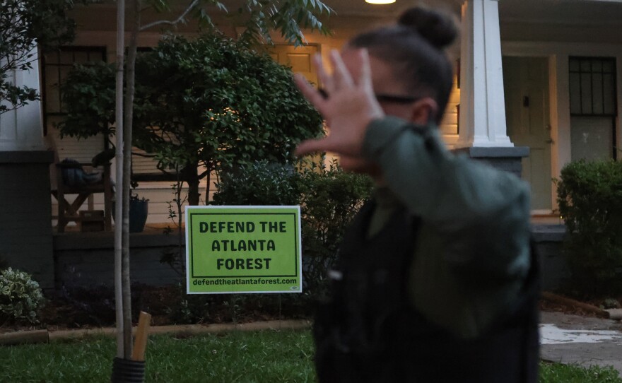 A law enforcement officer covers her face after marching through a gathering of activist at Brownwood Park who oppose the Atlanta Public Safety Training Center that protesters refer to as "Cop City," just as a vigil for killed activist Manuel "Tortuguita" Terán was set to begin, informing them the park will be closed at 11PM in Atlanta, Georgia, U.S., June 24, 2023.