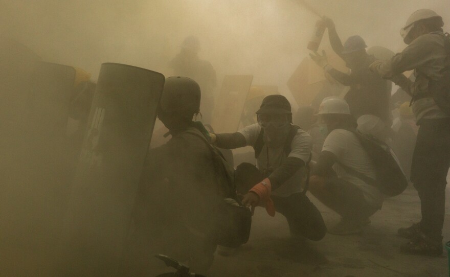 Protesters defend themselves with makeshift shields during clashes with riot police as the military government intensified its crackdown on demonstrations, on Feb. 28, in Yangon, Myanmar.