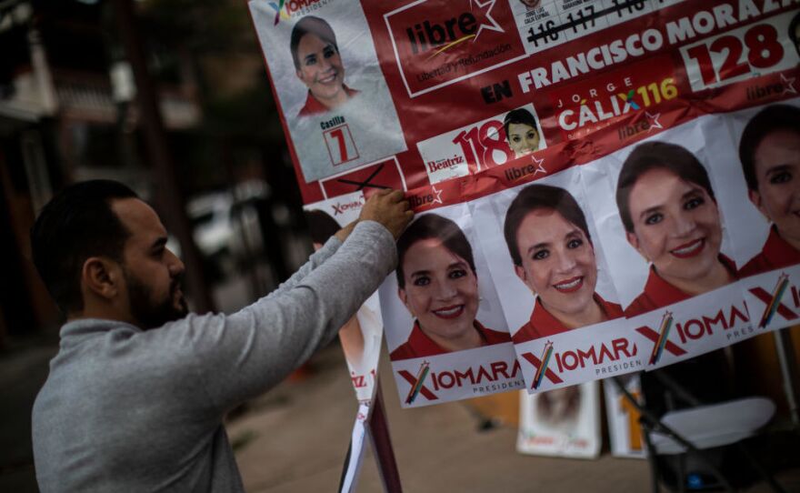 A supporter of the leading presidential candidate, Xiomara Castro, hangs campaign posters on Saturday in Tegucigalpa, Honduras.