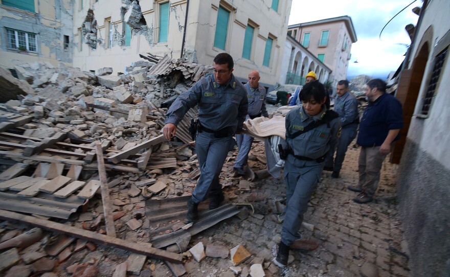 Rescuers carry a victim among damaged buildings after a strong earthquake hit Amatrice, Italy, on Wednesday.