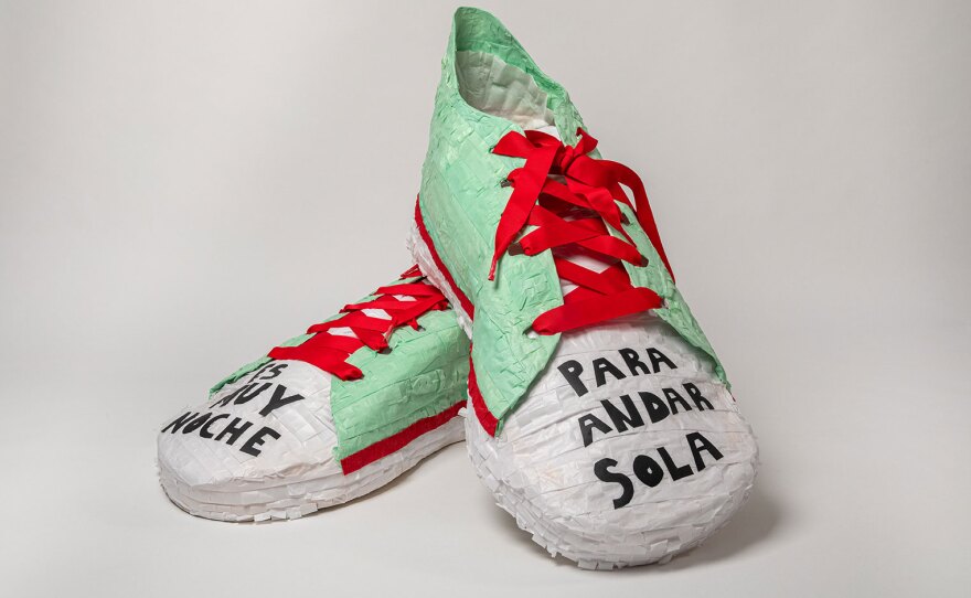 Diana Benavídez's piñata, "Es muy noche para andar sola," is shown in an undated photo. The title (and text across the toes of the shoes) translates to "it's too late to walk alone."