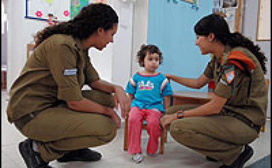 After a Qassam rocket attack by Palestinian militants from the Gaza strip, Israeli soldiers talk to a little girl at a nursery.