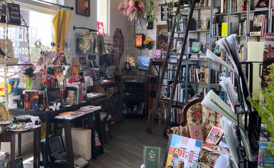 Interior of Libélula Books shows bookshelves and tables full of books and plants.